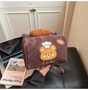 Close-up of brown suede crossbody bag featuring cartoon bear patch and plush handle