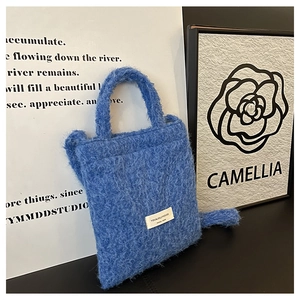 Close-up of blue fleece tote bag showing plush wool texture and designer woven label