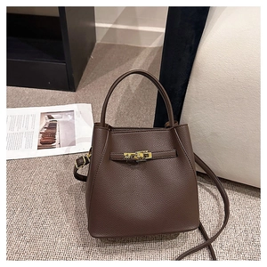 Detail of dark brown litchi pattern leather bucket bag with golden twist lock