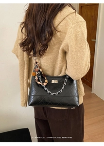 Close-up of quilted black shoulder bag with silver chain and vintage beaded charm detail