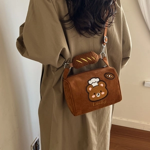 Detail of plush brown crossbody bag with bear embroidery and creative bread accessory