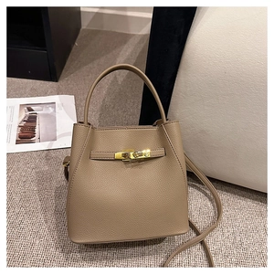 Detail of brown lychee grain leather bucket bag with gold hardware lock and strap