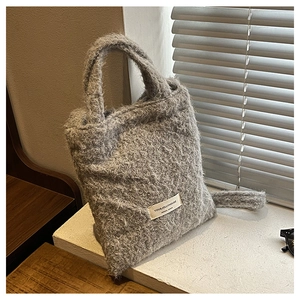 Detail of grey plush tote bag featuring woven YOU&JOLLYHOUSE label and fuzzy texture