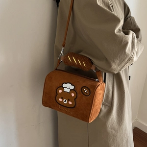 Close-up of brown plush pillow bag with bear embroidery and baguette accessory