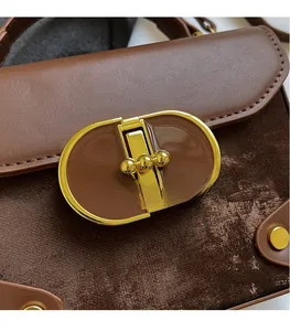 Detail of a brown two-tone handbag featuring smooth leather and suede texture with a gold clasp