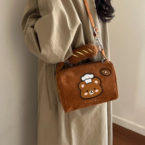 Detail of plush brown crossbody bag with bear embroidery and baguette charm
