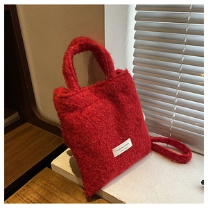 Close-up of fluffy red wool handbag featuring silver glitter fibers and a white textile label