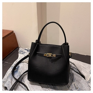Detail of black pebbled leather bucket bag with golden twist lock on denim background