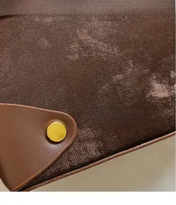 Close-up of brown faux suede fabric with leather trim and gold metal buckle detail