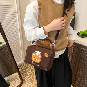 Detailed view of brown suede crossbody bag with bear embroidery and croissant charm