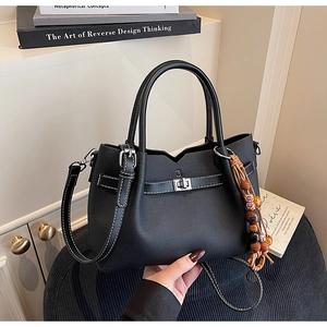 Détail du sac cabas en similicuir noir avec coutures blanches et glands en perles de bois