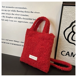 Detail of red wool fabric texture and white logo label on the chic fluffy bucket bag