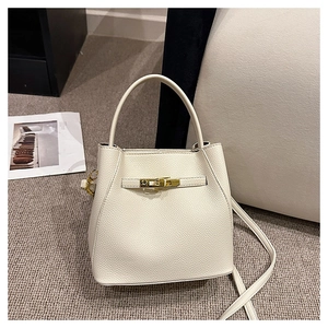 Detail of cream lychee leather bucket bag showing golden twist-lock and fine grain texture