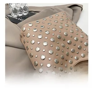 Close-up of beige leather bucket bag featuring silver rivet studs and industrial style
