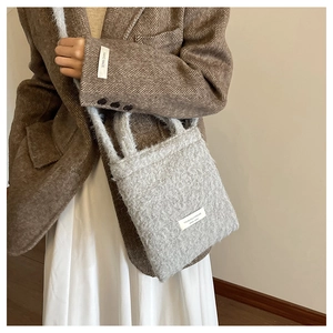 Detail of grey wool tote bag with white woven label on soft fuzzy textured fabric