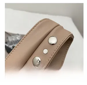 Detail view of khaki leather shoulder strap with silver rivets and stitching