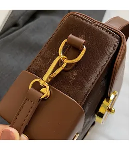 Detail of gold-tone metal hook and D-ring on brown leather and suede crossbody bag