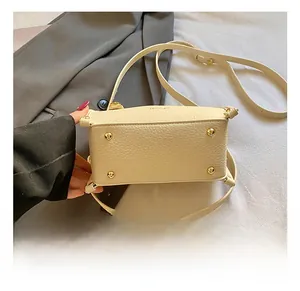 Detail of cream lychee leather handbag featuring four protective gold metal bottom studs