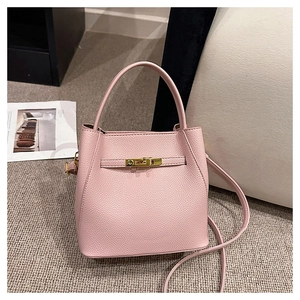 Detail of pink lychee textured leather bucket bag with gold twist lock and shoulder strap