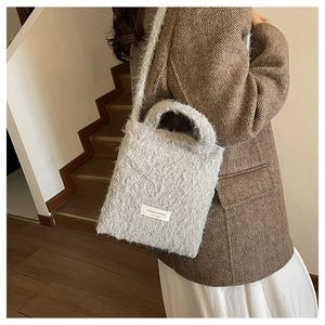 Detail of grey fuzzy crossbody bag showing soft faux fur texture and brand label