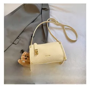 Detail of cream baguette bag with lychee texture, golden clasp and plush bear charm