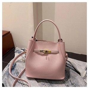 Detailed shot of pink pebble texture bucket bag with gold clasp on denim jacket