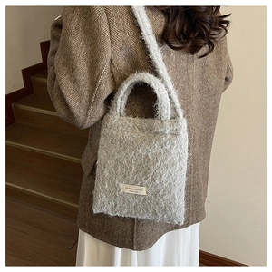Detailed view of gray plush bucket bag with brand label and soft fuzzy texture