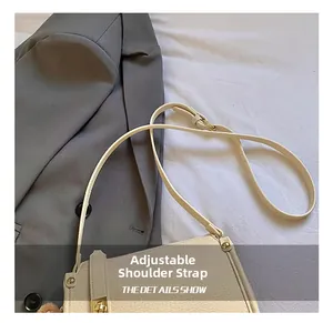 Detail of cream baguette bag with gold rotary buckle and adjustable leather strap