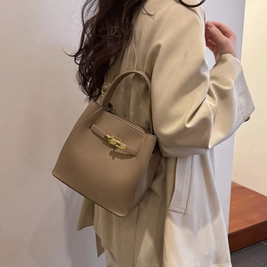 Detailed shot of textured leather bucket bag with gold lock buckle and handle