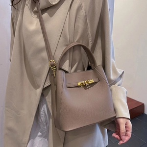 Detail of taupe leather bucket bag with gold twist lock on trench coat style