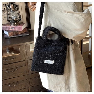 Detail of vintage black tweed tote bag with silver glitter thread and brand label patch