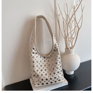 Detail of white hobo bag featuring silver punk rivets on a minimalist aesthetic background