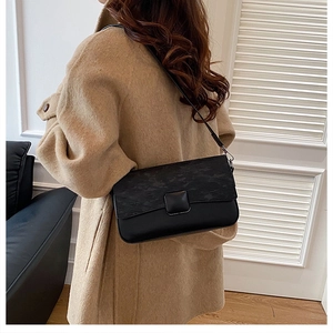 Detail view of a black flap shoulder bag featuring subtle textured patterns and a matte lock