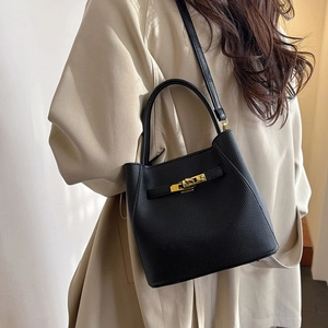 Detail of black pebbled leather bucket bag with gold twist lock and sturdy handle