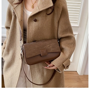 Detail of vintage brown shoulder bag with wood grain texture worn over a beige coat