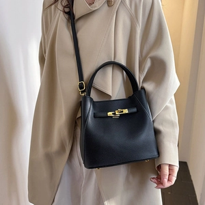 Detailed macro view of black lychee grain bucket bag with elegant golden rotary lock hardware
