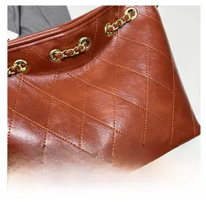 Detail showing brown quilted leather texture and gold chain strap of a classic tote bag