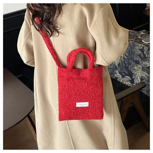 Macro detail of red fluffy wool handbag showing soft texture and woven logo tag