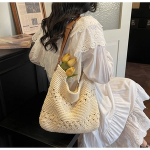 Close-up of a woven tote bag with flower cutouts and a brown leather strap details