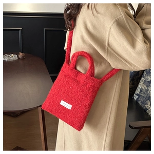 Model wearing a red plush bucket bag with wool texture and white brand label detail