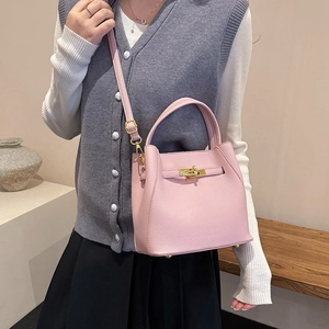 Detail shot of the pink lychee leather bucket bag with gold lock and metal feet