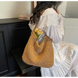 Detail of woven straw tote bag with 3D floral texture and brown leather strap
