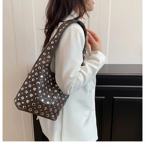 Détail du sac sous le bras en cuir marron avec clous argentés et large bandoulière confort