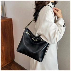 Detail of black quilted leather tote showing gold chain strap and diamond stitching