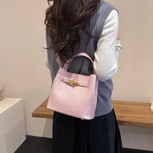 Rear view of a model carrying the pink lychee leather bucket bag with gold lock hardware