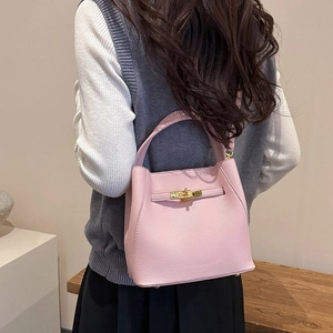 Close-up of pink lychee grain leather bucket bag with a golden metal twist lock detail