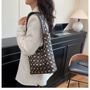 Detail of dark brown leather underarm bag featuring vintage silver rivet studs on a model