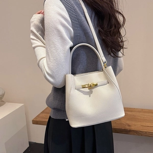 White lychee pattern bucket bag with gold hardware worn by a model in a casual setting