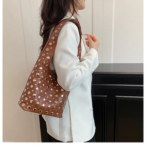 Detailed side view of a brown punk shoulder bag with silver studs on a female model