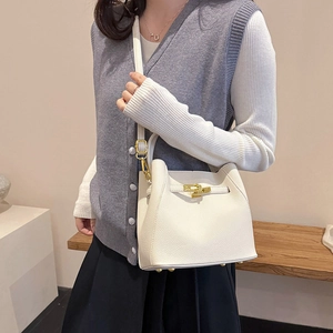 Close-up of white lychee pattern leather bucket bag with gold metal twist lock and studs